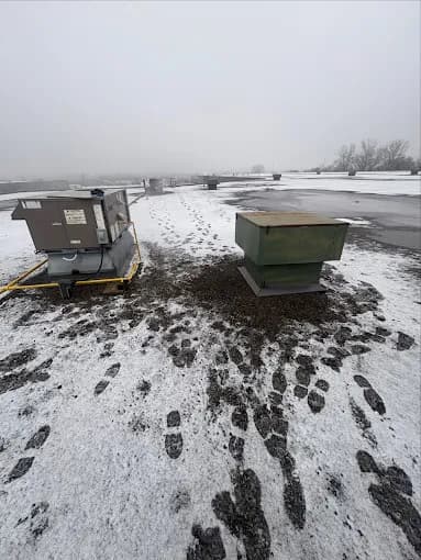 Commercial rooftop air conditioning units serviced by Cold Force Mechanical on a snow-covered flat roof